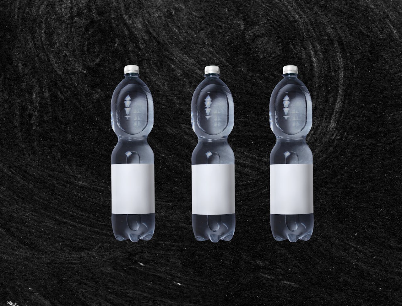 heros-img Plastic bottles of still spring water with white blank sticker placed against rough black background
